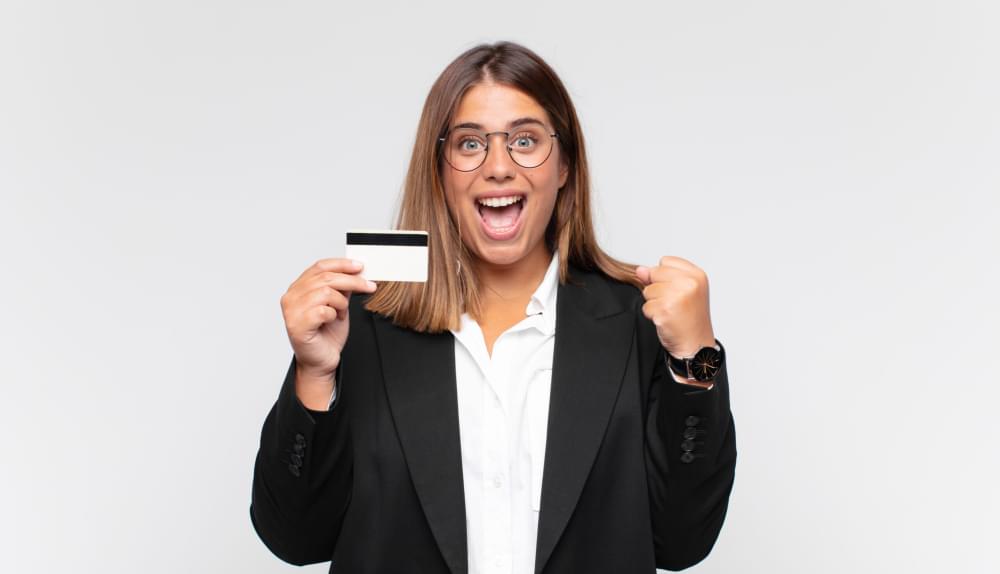 Young-woman-with-a-credit-card-feeling-shocked-excited-and-happy-laughing-and-celebrating-success-saying-wow-scaled-1.jpg