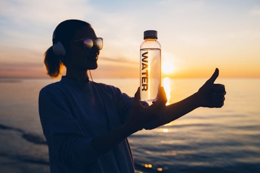 Woman-at-beach-sunrise-holding-bottle-of-water-showing-positive-gesture-thumb-up-sign_285396-10304-1.jpg
