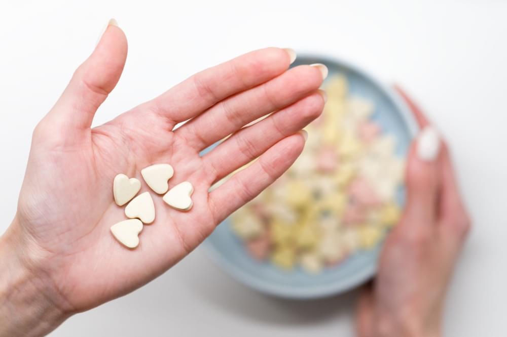 Close-up-of-woman-hold-heart-shaped-vitamins-or-mineral-pills-on-palm-blurred-hand-holding-bowl-of-colored-vitamins-scaled-1.jpg