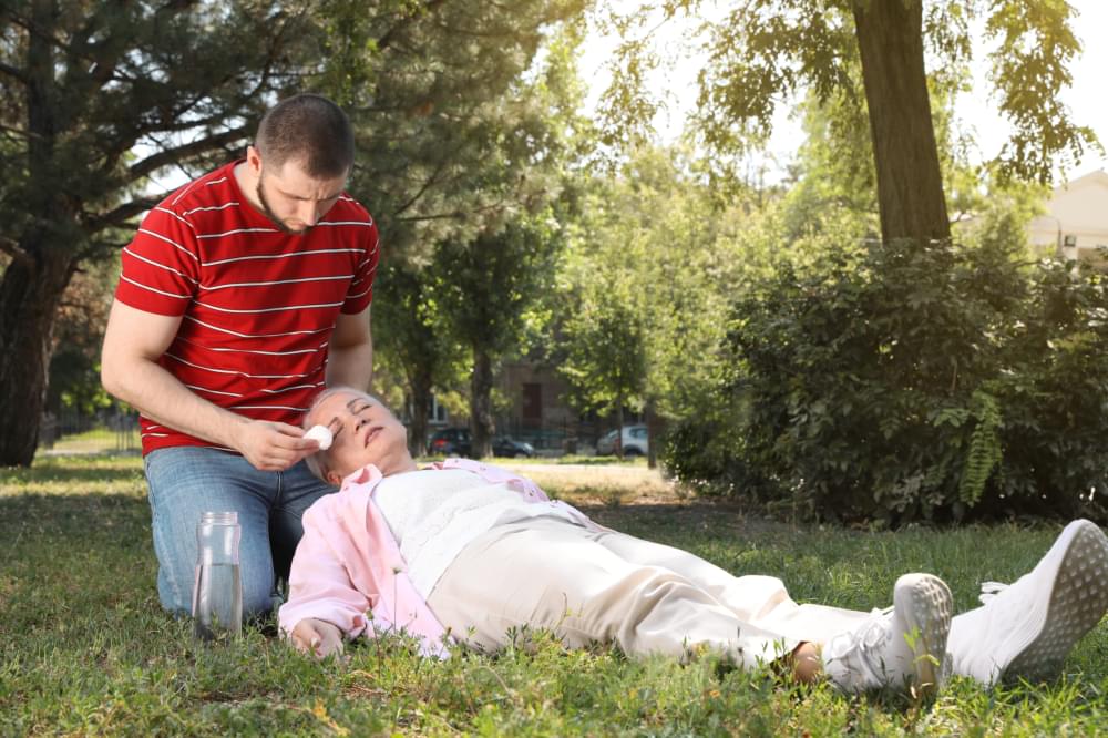 Man-helping-mature-woman-in-park-suffering-from-heat-stroke-scaled-1.jpg