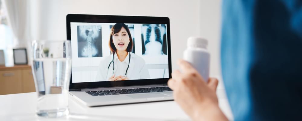 Young-asia-lady-using-computer-laptop-talk-about-disease-video-conference-call-with-senior-doctor-online-consultation-living-room-home-scaled-1.jpg